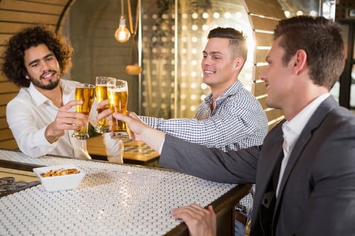 Group of friends toasting a glass of beer in bar